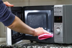 A person doing cleaning service of a microwave in Plano, TX