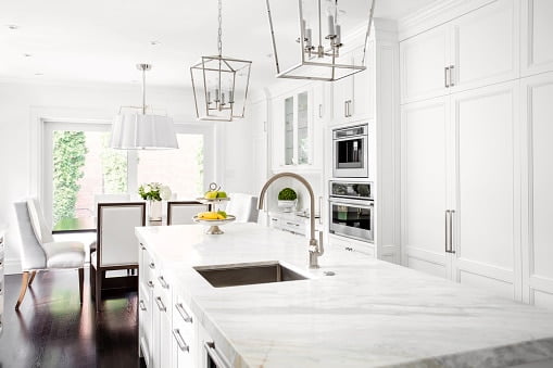 Bright horizontal image of classic white kitchen, with marble island.