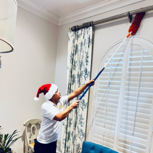 Dallas Sunrise Maids team member holding a mop, cleaning the top of a wall in Plano, TX