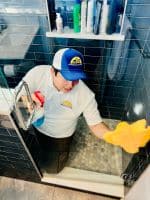 Dallas Sunrise Maids crew in a bathroom cleaning the shower door in Plano, TX