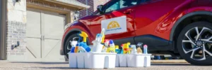 Professional house cleaning supplies organized in caddies next to Dallas Sunrise Maids service vehicle by Dallas Sunrise Maids in Plano