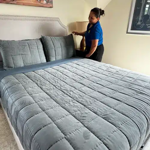 Professional tidying up a neatly made bed after house cleaning after death by Dallas Sunrise Maids in Plano TX