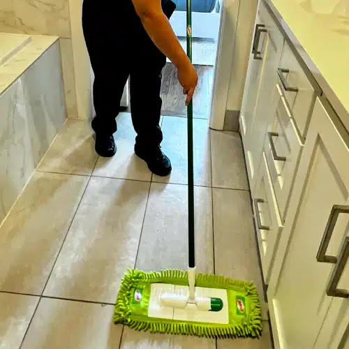 Professional mopping a bright tiled bathroom floor after house cleaning after death by Dallas Sunrise Maids in Plano TX