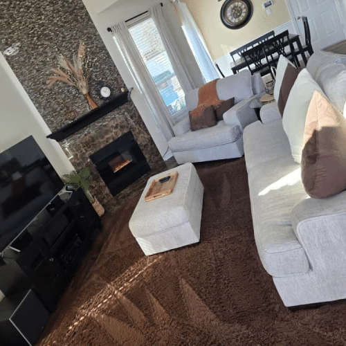 Freshly cleaned modern living room with sofa, TV, and fireplace after professional house cleaning by Dallas Sunrise Maids in McKinney