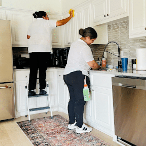 Two professional cleaners wiping cabinets and countertops during house cleaning McKinney by Dallas Sunrise Maids in Frisco