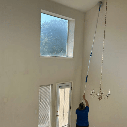 Professional cleaner dusting high ceiling corners during house cleaning McKinney by Dallas Sunrise Maids in Frisco