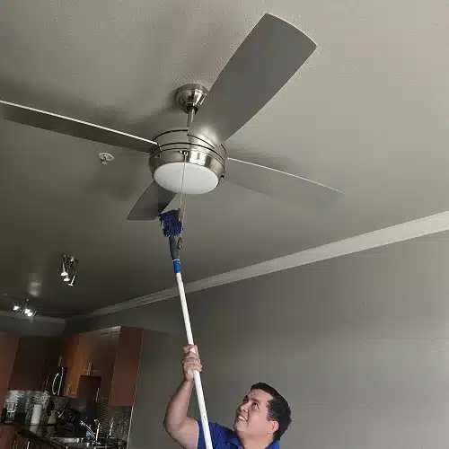 Professional cleaner dusting ceiling fan during a house cleaning Addison, TX service by Dallas Sunrise Maids in Texas