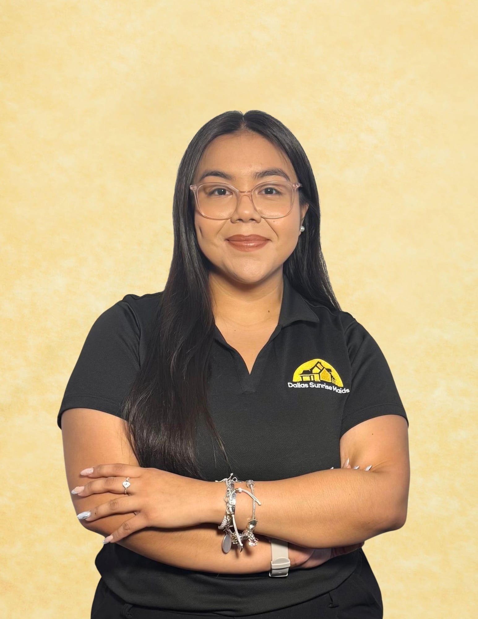 Sandra from Dallas Sunrise Maids wearing a black collared shirt with company logo, standing confidently with arms crossed in Plano, TX.
